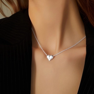 Elegant silver heart pendant necklace on minimalist chain worn with professional suit