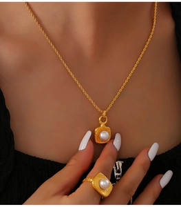 Detail view of vintage square pearl necklace and ring set on model in gold titanium steel