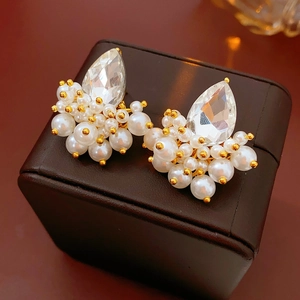 Macro shot of gold teardrop crystal earrings with white pearls on brown leather