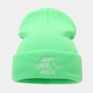 Detail of neon green knitted beanie featuring silver DON'T FORGET TO SMILE embroidery
