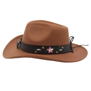 Détail d'un chapeau de cowboy en feutre marron avec bandeau brodé et boucle de tête de taureau