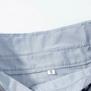 Détail de la taille en sergé bleu clair avec étiquette de taille S blanche cousue