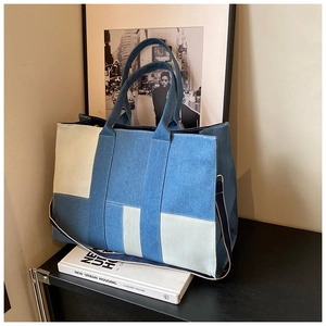 Close-up of patchwork denim tote bag with canvas stitching and sturdy metal hardware