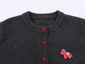 Detail of grey knit cardigan with red buttons and embroidered horse on the chest
