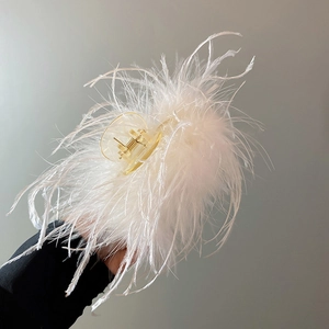 Close-up of white ostrich feather hair claw clip with transparent acrylic base