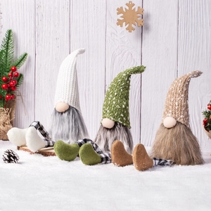 Three long-legged Christmas gnomes with plaid hats and fur beards on white wood background