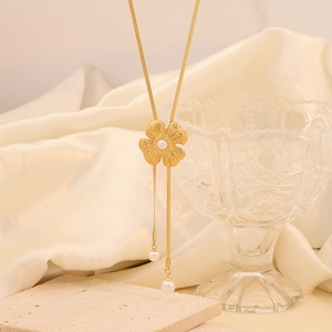 Detailed shot of golden flower pendant necklace with elegant pearl charms on silk