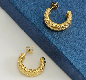 Detail of gold twisted C-shape hoop earrings with a polished textured finish and studs