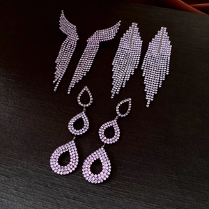Macro shot of silver-tone hollow teardrop earrings with pink rhinestones and fringe