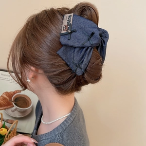 Detail of large denim bow hair claw with bear label shown on model hairstyle