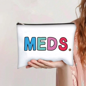 Detail of white canvas makeup bag featuring colorful MEDS. print with black zipper
