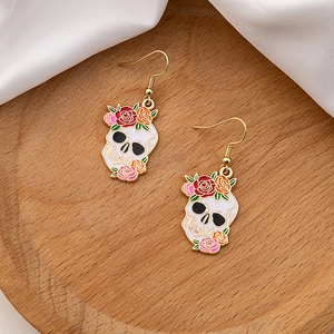 Detailed macro view of skull earrings with colorful flowers on a premium wooden tray