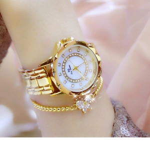 Detail of BS Bee Sister gold watch with white dial and flower pendant bracelet on wrist