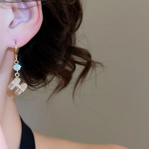 Close-up of 14K gold plated H-letter earrings with shimmering cubic zirconia and pearls