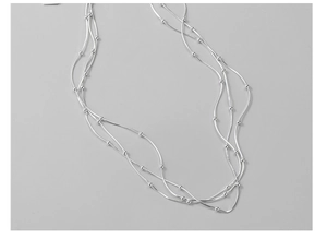 Detail of silver triple-layered snake chain necklace with small metal beads