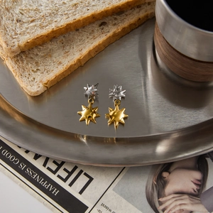 Detail of gold sun charms and silver starburst earrings on a metallic tray
