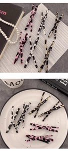 Close-up of leopard print bow hair clips in pink and beige on a stylish desk setup