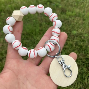 Schlüsselanhänger mit Baseball-Holzperlen und Armband auf grünem Rasenhintergrund
