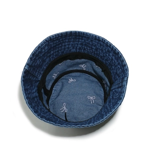 Detailed interior of denim bucket hat showing white bow embroidery and sweatband