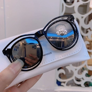 Detail of black round kids sunglasses featuring white leather case with Monster logo