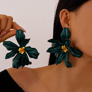Close-up of large deep green acrylic flower earrings with yellow beaded centers on model