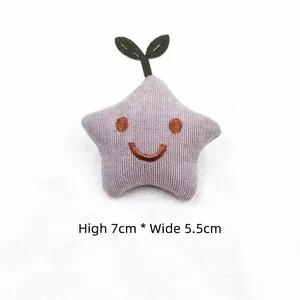 Detail of star-shaped fabric plush accessory with smiley face and green sprout sprout