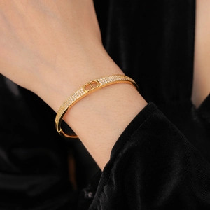 Close-up of gold-plated bangle with pave-set cubic zirconia and CD letter emblem detail