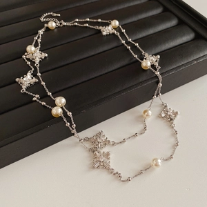 Détail du pendentif croix argenté serti de diamants et perles sur collier élégant
