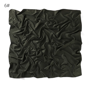 Detail of dark green satin square scarf, smooth texture and soft drape fabric closeup.