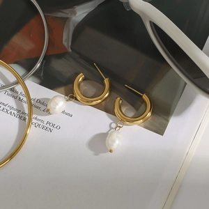 Detalle de pendientes de aro dorados vintage con grandes perlas barrocas blancas