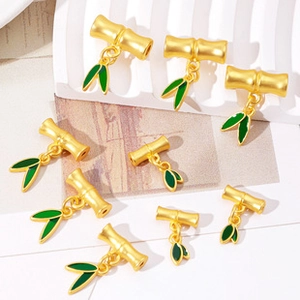 Macro detail of gold bamboo stem pendants with green enamel leaves for DIY jewelry making