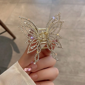 Close-up of golden butterfly hair claw clip with sparkling rhinestones and hollow wings