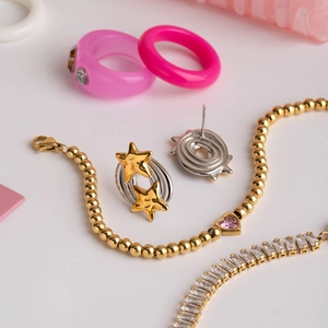 Vue à plat de boucles d'oreilles étoiles, bracelets roses et bagues de mode colorées