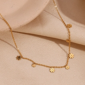 Macro shot of gold floral pendants on a minimalist chain over a textured beige fabric