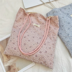 Detail of pink and blue tote bags featuring white lace mesh and pearl embellishments
