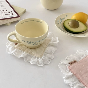Close-up of embroidered lace coaster with textured fabric and soft scallop edges