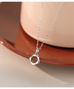 Detailed macro view of S925 sterling silver hollow flower pendant necklace on ceramics