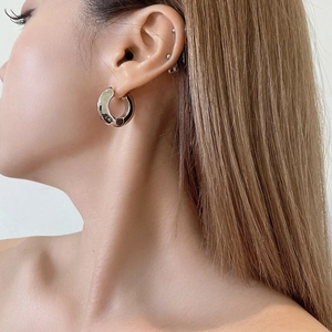 Macro shot of a thick silver polished hoop earring on model showing metallic texture
