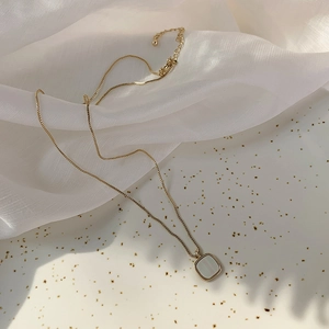 Elegant gold square shell necklace for women on white silk with leaf shadow