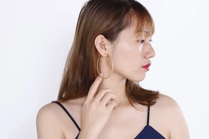 Nahaufnahme großer goldener Creolen am Modell mit glattem Metallfinish und minimalistischem Stil