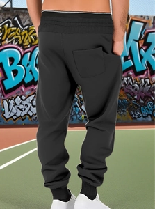 Rear view of black joggers showing elastic waistband and back pocket on urban background