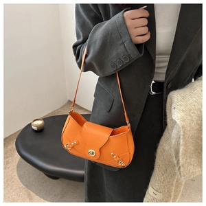 Chic orange faux leather shoulder bag with metallic buckle and rivet details shown on model
