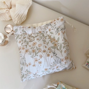 Détail du motif floral de lapin sur pochette de rangement en coton crème à cordon