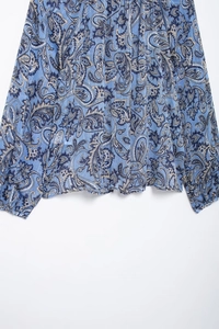 Dettaglio della camicetta in chiffon paisley blu con trama del tessuto e polsini in pizzo