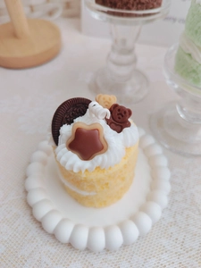 Detail of a strawberry sponge cake candle with bear and biscuit topper on a white tray