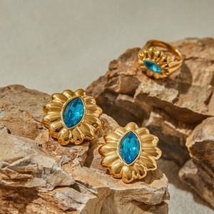 Macro shot of gold-plated rings and earrings with blue gemstones on natural stone