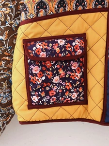Close-up of diamond quilting on yellow cotton jacket with floral print pocket detail