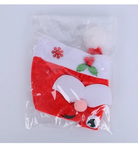 Detail of a Santa Claus hat featuring sequins and holly berries in plastic packaging