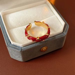 Close-up of gold-plated wavy ring with red enamel inlay inside a velvet jewelry box