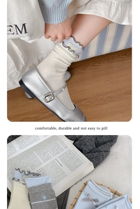 Dettaglio di calze di cotone bianco con ricamo a fiocco e scarpe Mary Jane argentate